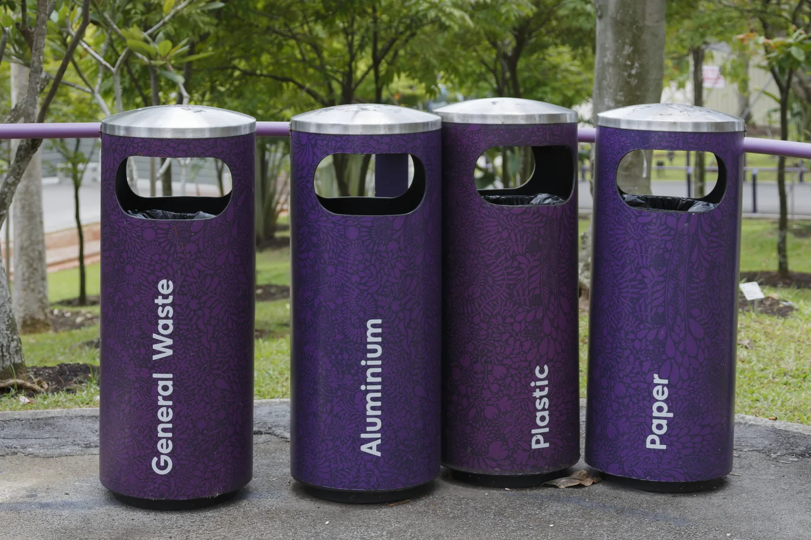 Four recycling bins for general waste, aluminium, plastic and paper in a garden in Singapore