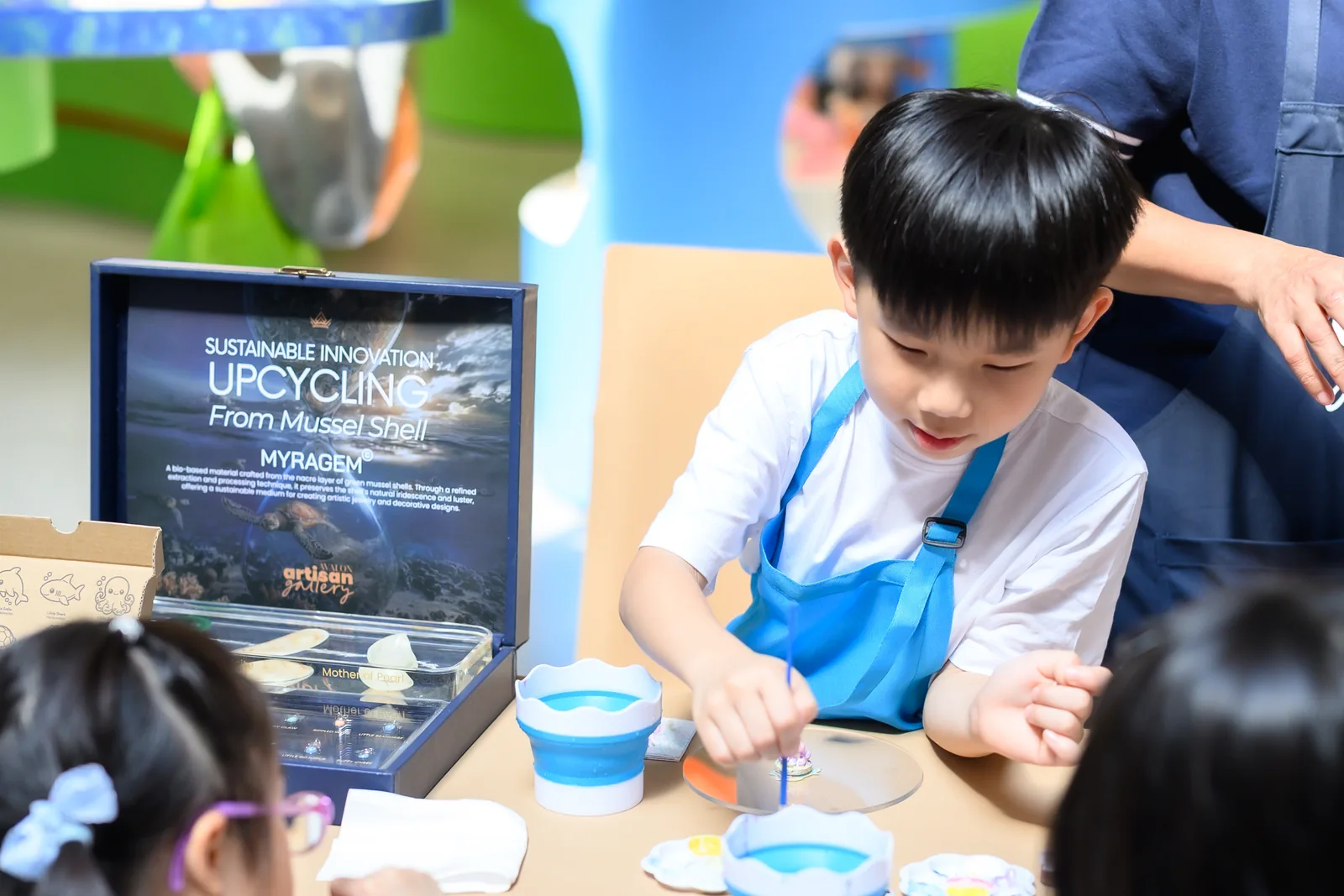 A child paints a MyraShell sea creature at the workshop